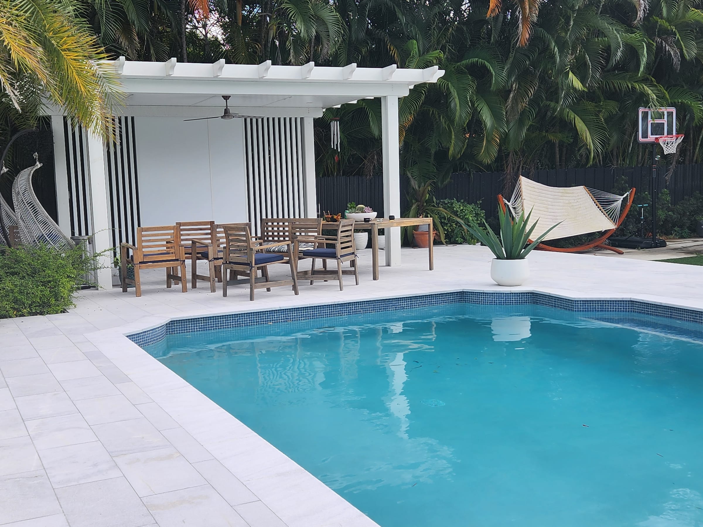 Pérgola de aluminio blanco con comedor de exterior instalada junto a la piscina