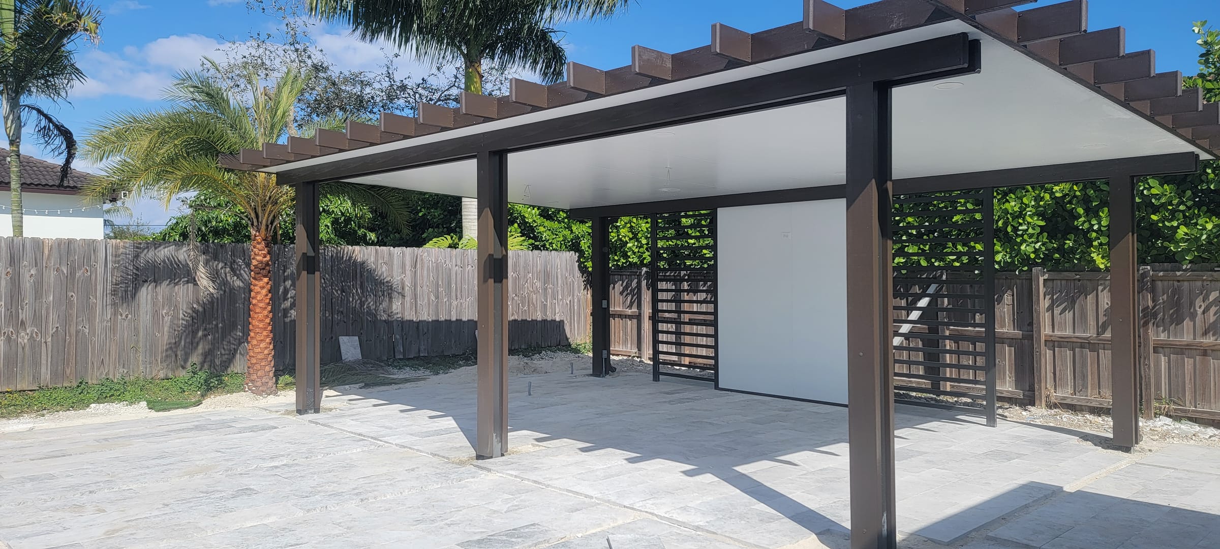 Pérgola de aluminio bronce con techo blanco y paneles de privacidad